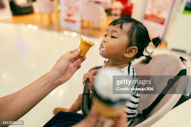 positive emotion asian baby girl happy to eating ice cream first time and cream messy on her mouth - eating ice cream sandwich stock pictures, royalty-free photos & images
