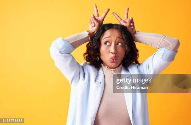 femme drôle, enjouée et maladroite avec des doigts sur la tête comme des oreilles de lapin. portrait d’une femme folle, élégante et gaie avec un espace de copie surpris sur un fond orange vif - la folie des grandeurs photos et images de collection