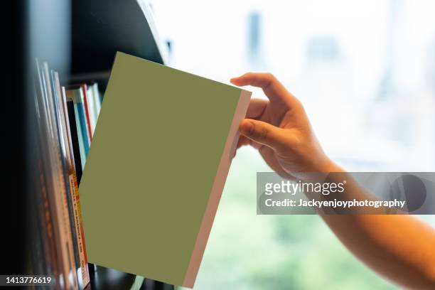 a hand takes out a book from the shelf - shelf strip stock pictures, royalty-free photos & images