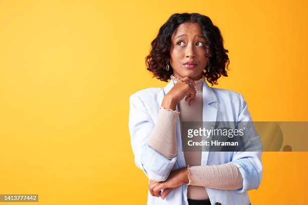 thinking, wondering and considering woman looking thoughtful and pensive isolated against a yellow studio background. trendy, stylish and young african female worried about future with copy space - confuso imagens e fotografias de stock