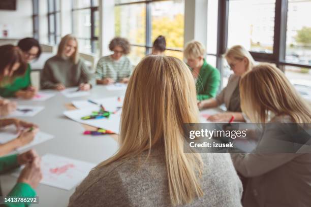 blond businesswoman looking at colleagues in office - office woman blond stock pictures, royalty-free photos & images