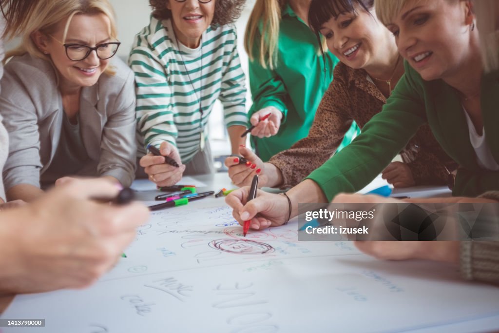 Colleagues writing with felt tip pens on paper