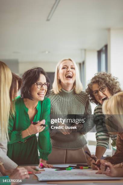 compañeras felices durante la reunión en la oficina - animar equipo fotografías e imágenes de stock