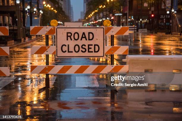 road closed sign with colourful stop lights and traffic lights reflected on wet road - road closed stock pictures, royalty-free photos & images