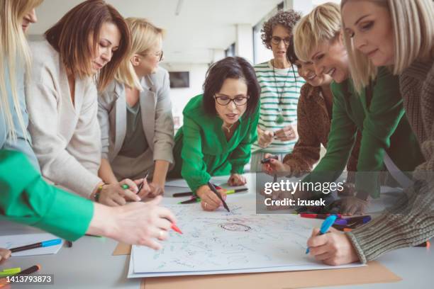 mature female colleagues sharing ideas on paper - creative writer stock pictures, royalty-free photos & images