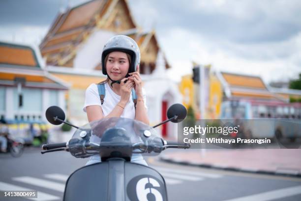 woman on scooter tightens helmet - moped stock-fotos und bilder