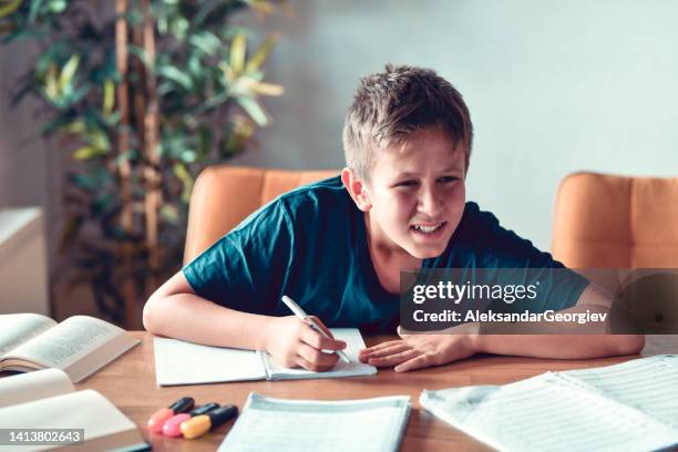 occhio che strizza gli occhi del bambino che guarda lo schermo mentre studia e scrive i compiti - miopia foto e immagini stock