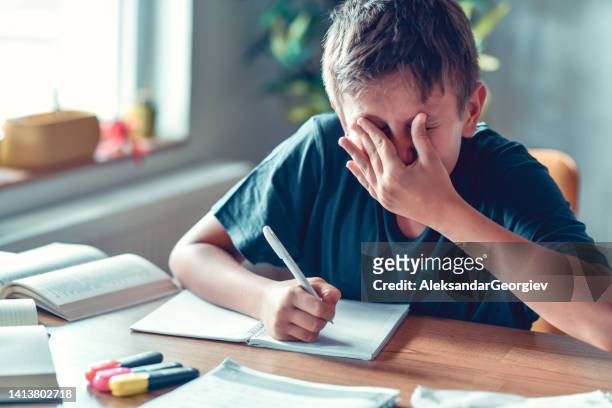 eye rubbing to eliminate sore eyes after trying to write homework with myopia by child - squinting stock pictures, royalty-free photos & images