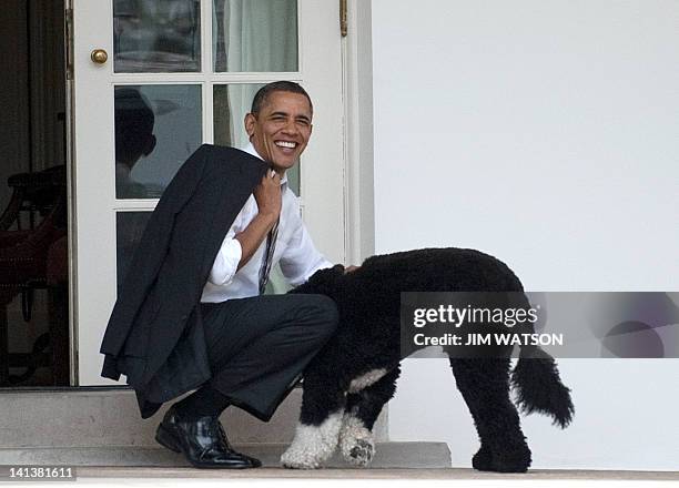 President Barack Obama pets the family dog, Bo, upon his return to the White House in Washington, DC, on March 15, 2012. AFP PHOTO/Jim Watson