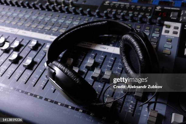 headphones, amplifying equipment, studio audio mixer knobs and faders. sound engineering equipment. selective focus. the photo is covered with sand and noise. wireless and electronic technologies. equipment in a nightclub, on television, radio studio. - radio hardware audio stock pictures, royalty-free photos & images