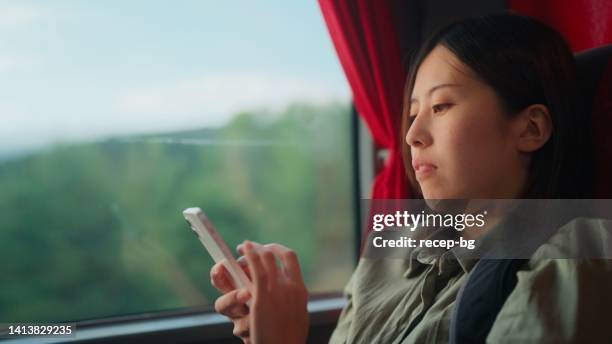 young female tourist sitting at window seat in bus and using her mobile phone - fast typing stock pictures, royalty-free photos & images