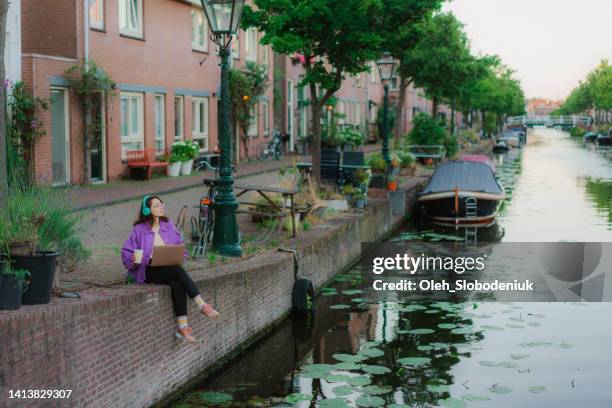 woman sitting with laptop on the canal and working - north holland stock pictures, royalty-free photos & images