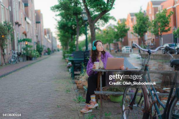 donna seduta al tavolo all'aperto e che lavora con il laptop - utrecht foto e immagini stock