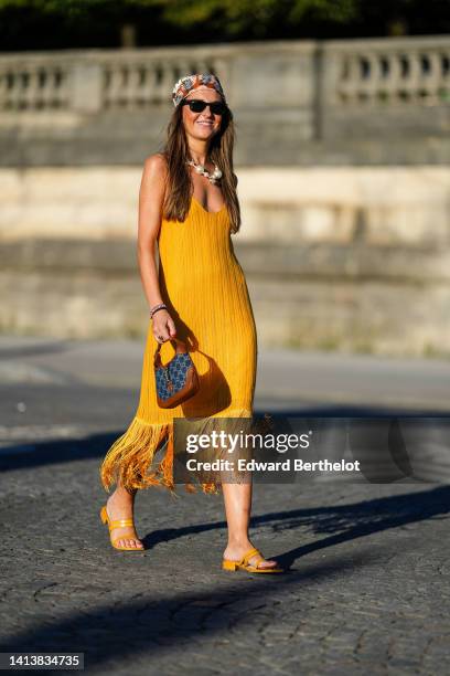 Alba Garavito Torre wears a brown with camel and white print pattern silk scarf as a head band from Lollys Laundry, black sunglasses from Ray Ban,...