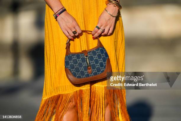 Alba Garavito Torre wears a yellow V-neck / sleeveless / midi dress with fringed borders from Zara, gold bracelets, gold rings, a brown shiny leather...