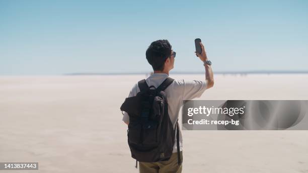 junger männlicher tourist, der mit seinem handy videos und fotos auf weißem salz in salt lake macht - 360 people stock-fotos und bilder
