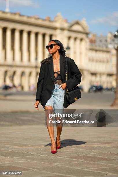 Emilie Joseph @in_fashionwetrust wears black sunglasses, diamonds earrings, a black flower print pattern lace corset top, a black oversized blazer...