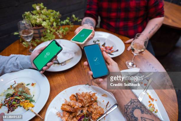 transferring money via an app - paying for dinner imagens e fotografias de stock