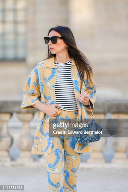 Gabriella Berdugo wears black square sunglasses, silver and black rhinestones in shape of heart earrings, a silver chain with diamond pendant...