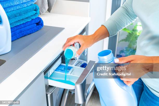 frau, die einer waschmaschine weichspüler oder waschmittel hinzufügt - laundry detergent stock-fotos und bilder