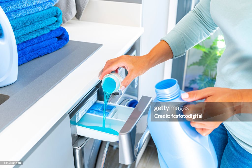 Woman adding fabric softener or detergent to a washing machine
