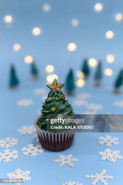 christmas cupcake. sweet christmas tree-shaped cupcake on a snowflake background - christmas cake foto e immagini stock