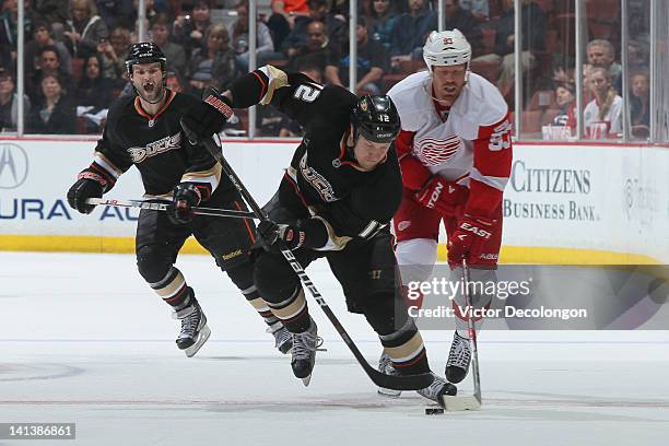 Niklas Hagman of the Anaheim Ducks controls the puck through the netural zone as he takes a slash from Johan Franzen of the Detroit Red Wings during...