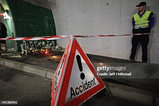 Police officer stands next to floral tributes laid by the families at the scene in the road tunnel where the 22 Belgian school children, four...