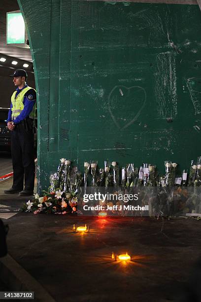 Police officer stands next to floral tributes and clandles laid by the families at the scene in the road tunnel where the 22 Belgian school children,...