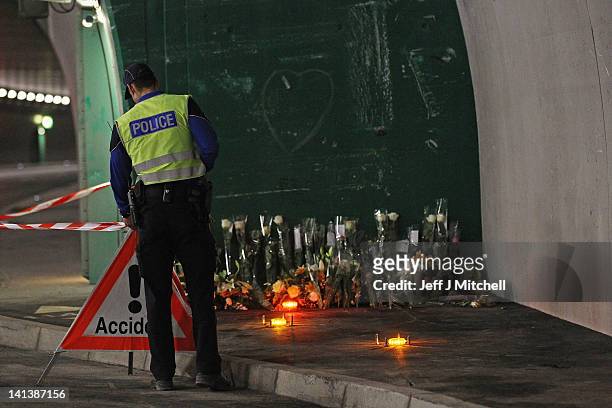 Police officer stands gaurd near floral tributes laid by the families at the scene in the road tunnel where the 22 Belgian school children, four...