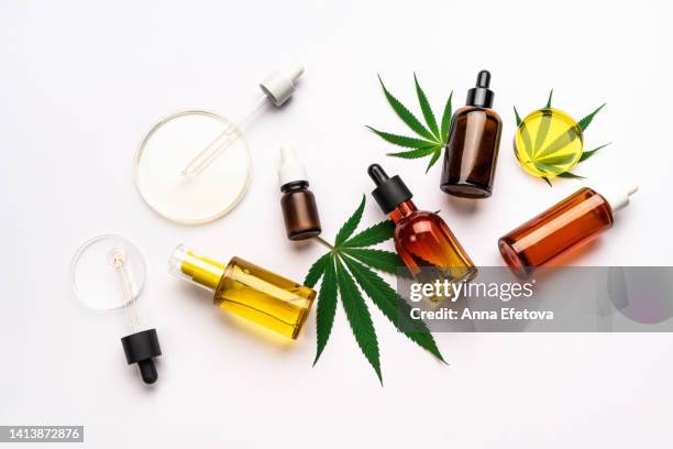 many cosmetic glass bottles, pipettes and petri dishes on leaves of cannabis on white background. concept of laboratory researches about using cannabidiol and hemp oil in cosmetology and dermatology. flat lay style - cbd oil stock pictures, royalty-free photos & images