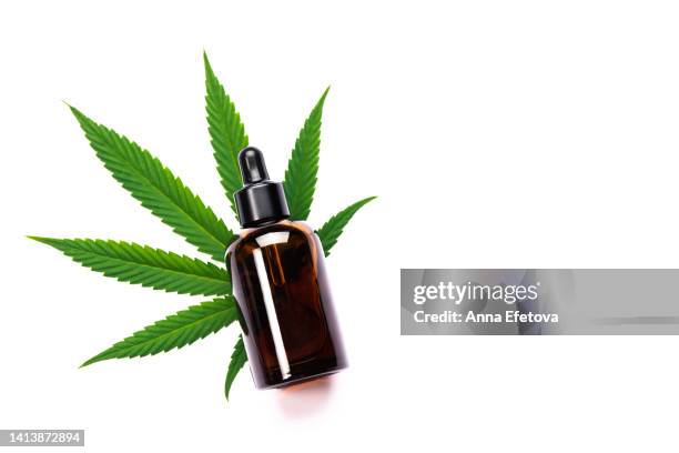 cosmetic glass bottle on leaf of cannabis on white background. concept of using cannabidiol and hemp oil in cosmetology and dermatology. photography from above - cbd products stock pictures, royalty-free photos & images