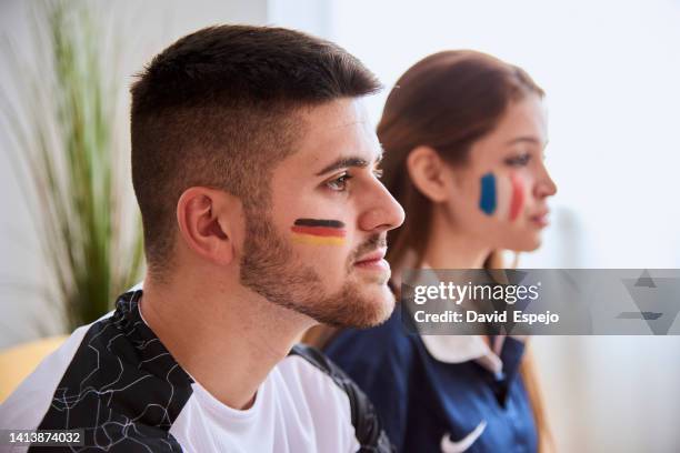 man and woman supporting their soccer team while watching a world cup match together. - face paint stock-fotos und bilder