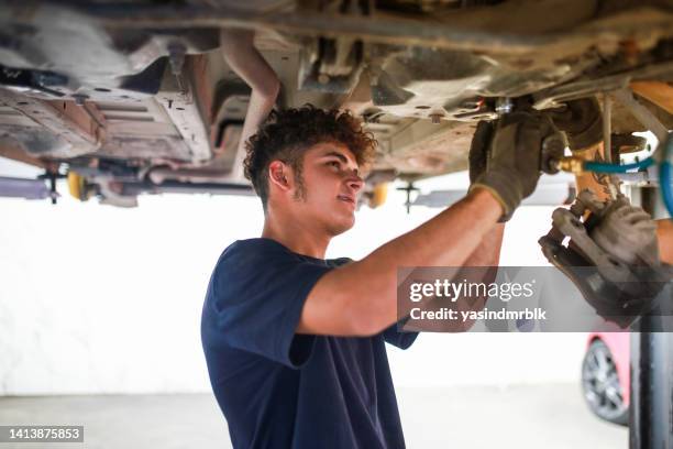 giovane tecnico addetto alla manutenzione della parte anteriore dell'auto. manutenzione ordinaria auto - pezzo di ricambio foto e immagini stock