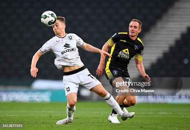 Dan Kemp of MK Dons controls the ball as Robert Milsom of Sutton United looks on during the Carabao Cup First Round match between Milton Keynes Dons...