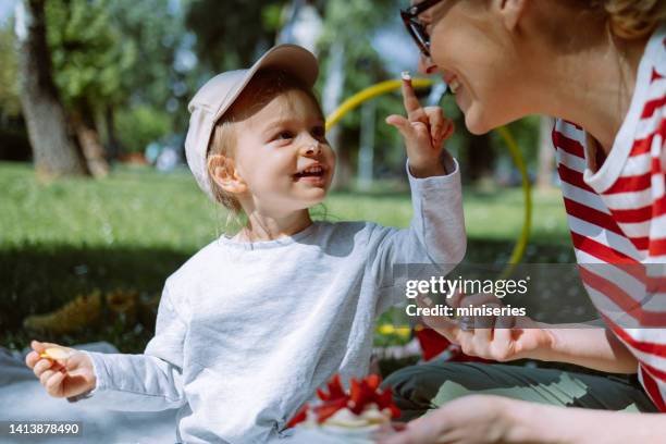 mother and daughter having fun while eating dessert together at picnic - throw cake stock pictures, royalty-free photos & images