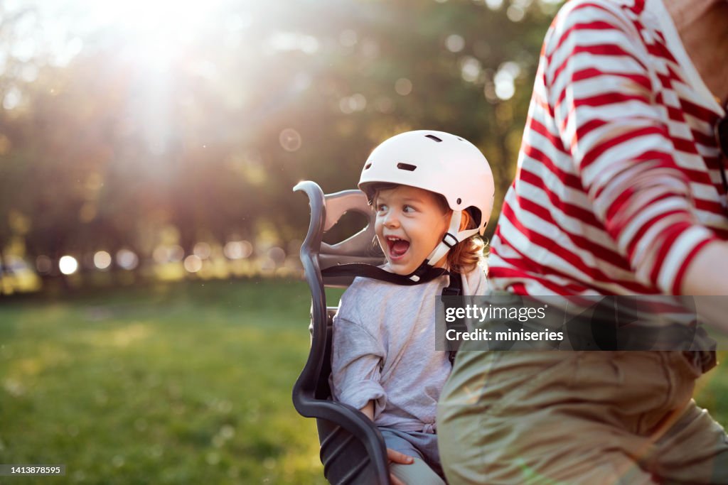Unrecognizable Mother Riding Her Daughter On A Bicycle In The Park