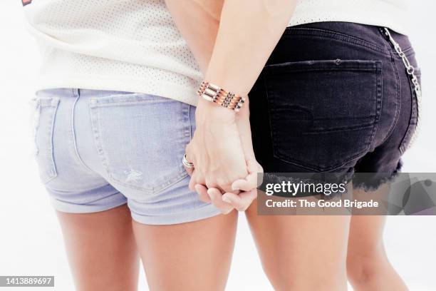 rear view of women holding hands in studio - buttocks gay stock-fotos und bilder
