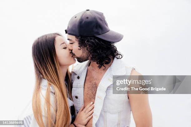 studio shot of young couple kissing against white background - romantic couple on white background stock-fotos und bilder