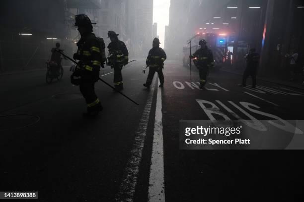Firefighters respond as smoke engulfs Fifth Avenue, blocks away from Trump Tower, as a fire breaks out in a building under construction on August 09,...