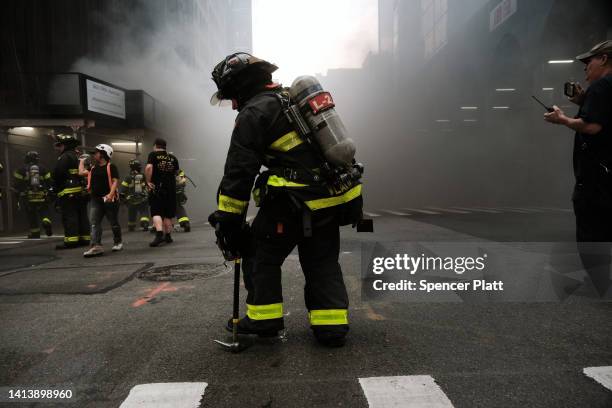 Firefighters respond as smoke engulfs Fifth Avenue, blocks away from Trump Tower, as a fire breaks out in a building under construction on August 09,...