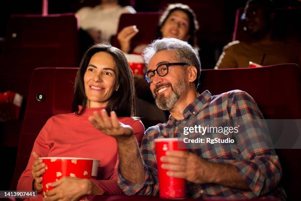 portrait of a happy mature couple watching a relaxing movie at the cinema - photograph 51 play stockfoto's en -beelden