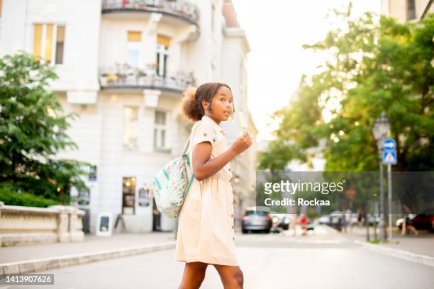 portrait of a cute girl with a backpack going to school - cross road children stockfoto's en -beelden