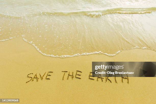 sign "save the earth" handwritten on sandy beach. copy space background. climate change and environment pollution concept. - plastic free stock pictures, royalty-free photos & images