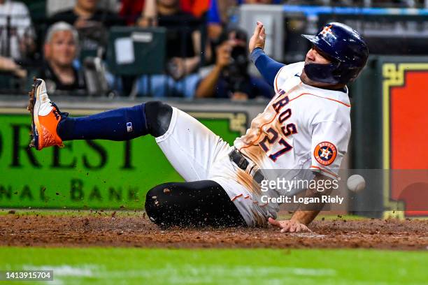 Jose Altuve of the Houston Astros slides into home to score a run in the fifth inning against the Texas Rangers at Minute Maid Park on August 09,...