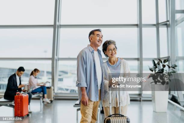 smiling asian senior couple tourists in airport - couple airplane stockfoto's en -beelden