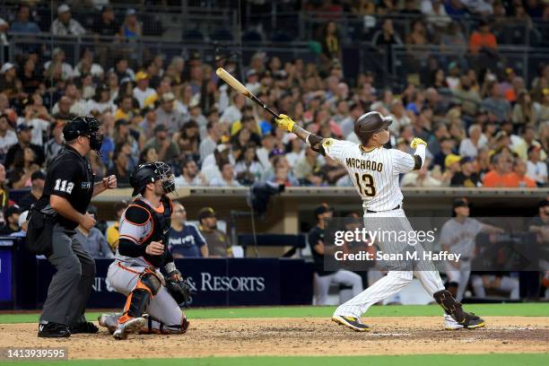 Manny Machado of the San Diego Padres hits a three-run homerun as Austin Wynns of the San Francisco Giants looks on during the ninth inning of a game...