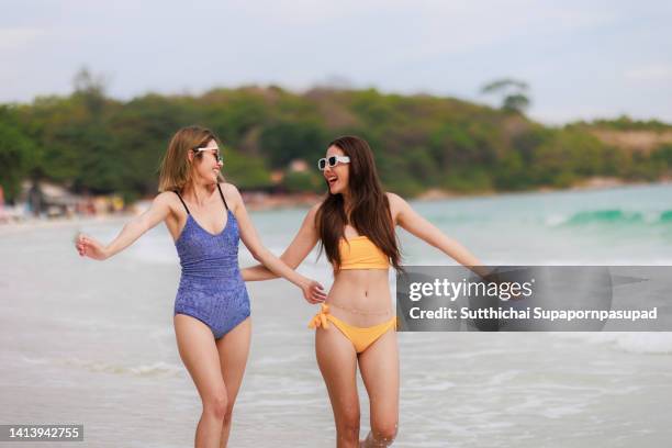 portrait of  happy asian female couple in swimsuit walking on the beach. holiday and vacation concept. - asian lesbians kiss stock pictures, royalty-free photos & images