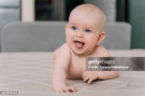 cute nude baby is lying on a light beige blanket at home. - baby boy and girl stock pictures, royalty-free photos & images