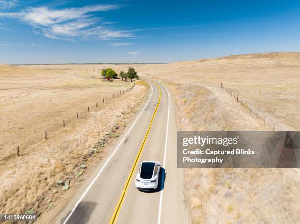 tesla model y electric suv driving on an open road with open farmlands around - tesla model s stock pictures, royalty-free photos & images